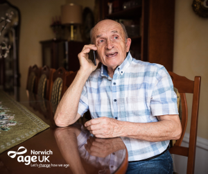 Older Man on the phone with Age UK Norwich logo overlay 