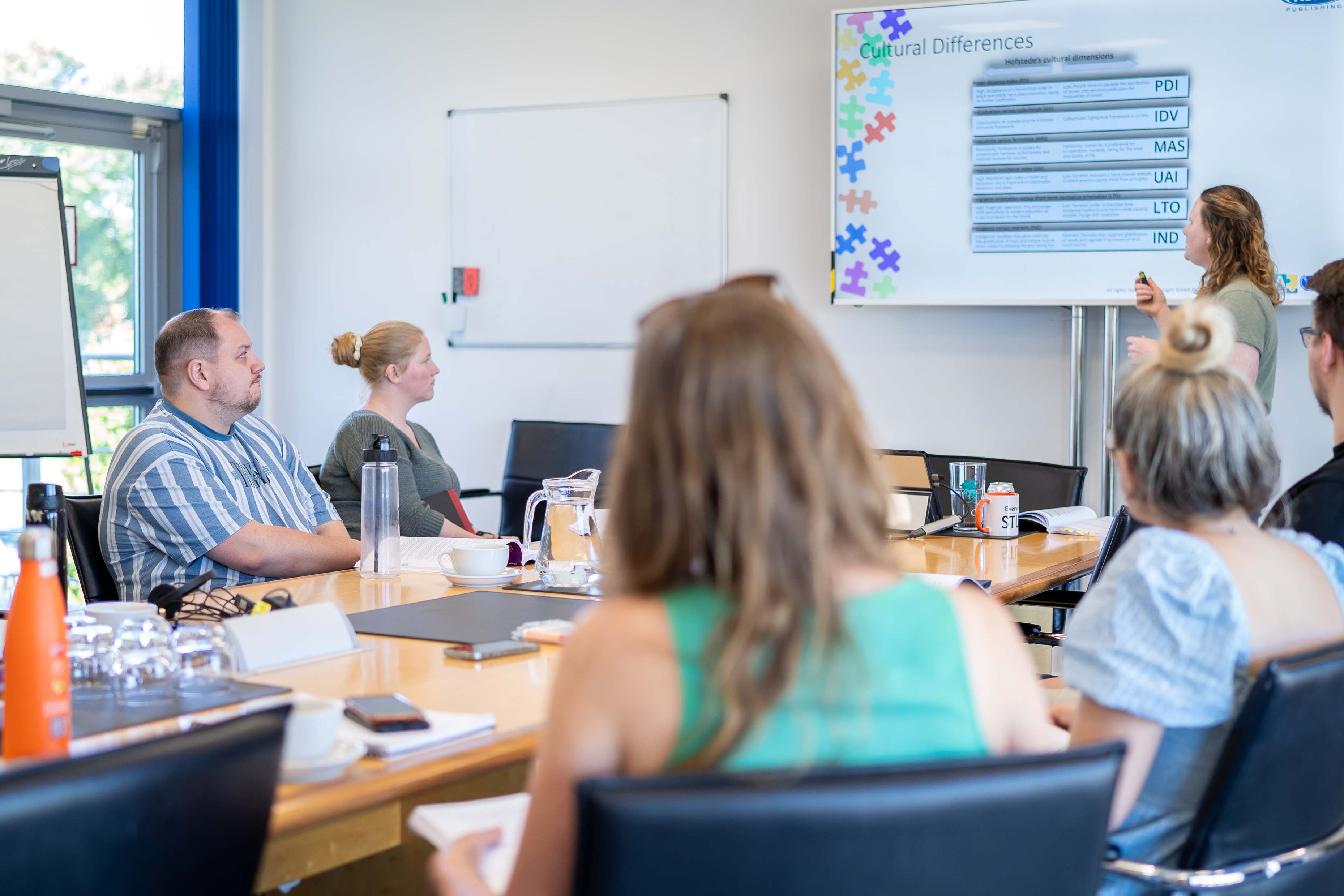 Photo of a classroom with adults sat around a table.