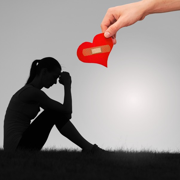 lady seated being offered a heart with a sticking plaster