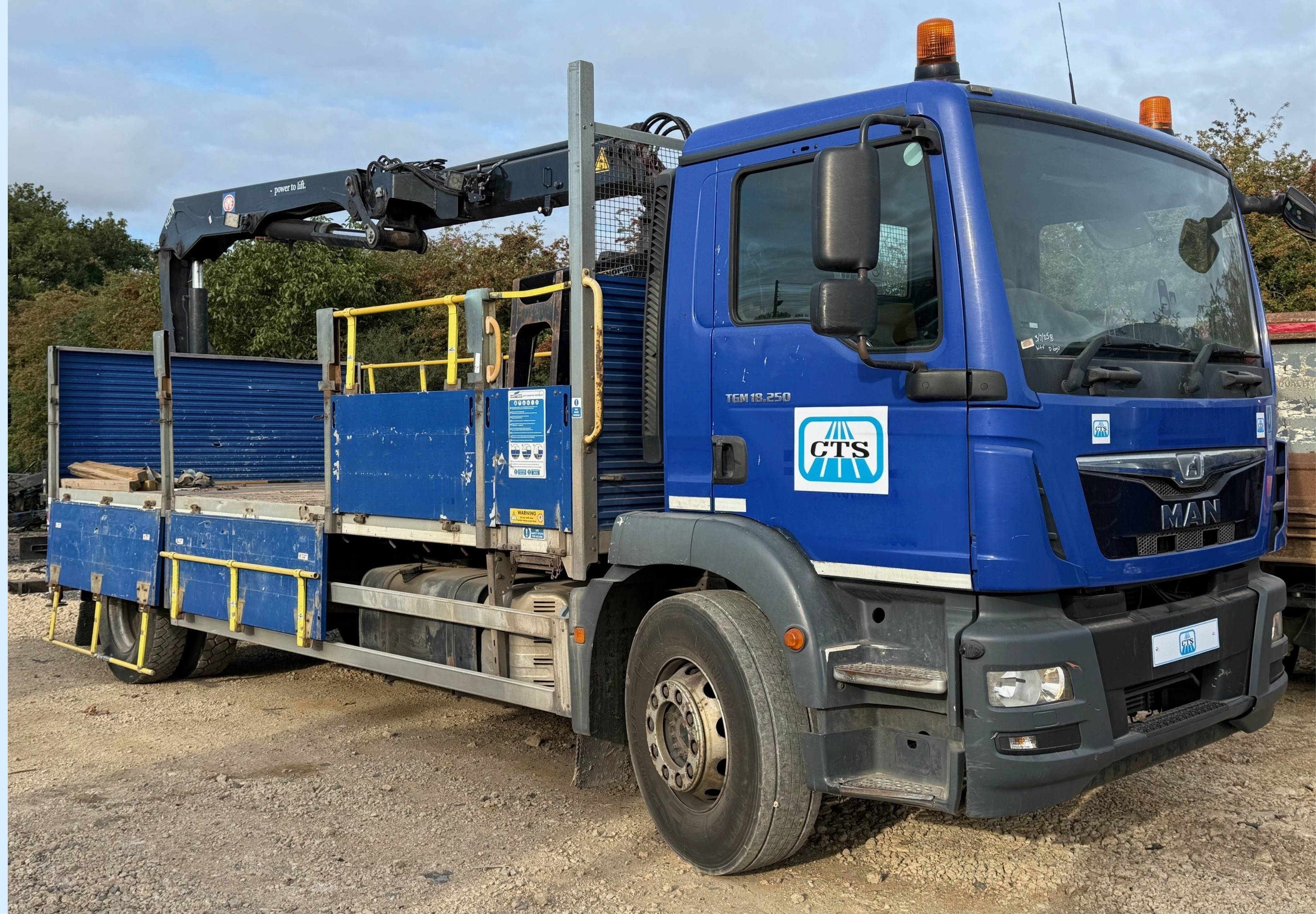 A blue hydraulic lorry loader with brick grab attachment.