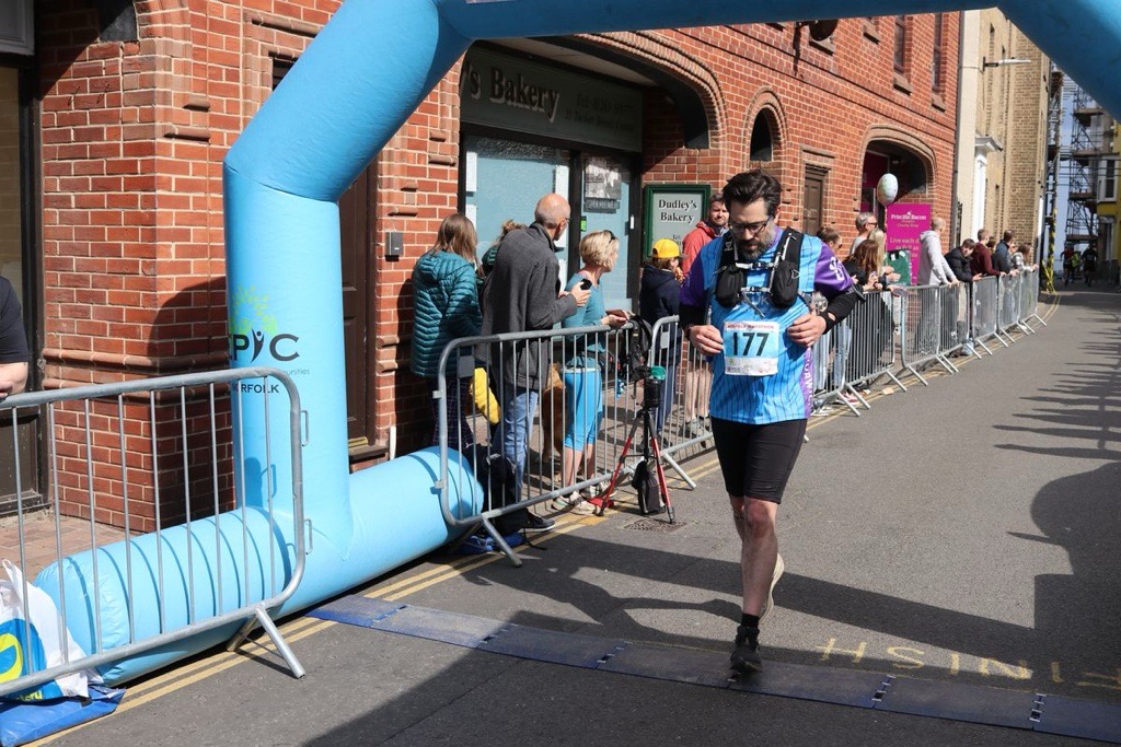 Age UK Norwich fundraiser going over the finish line at the Norfolk Marathon. 